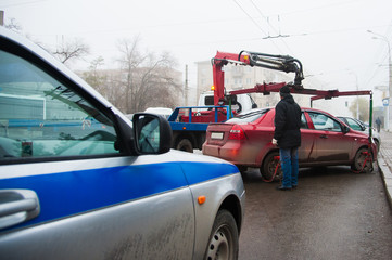 Traffic police officers on the street lifting the car on the tow truck