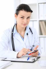 Fototapeta na wymiar Young brunette female doctor at working place in hospital. Health care, insurance and help concept