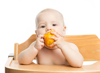 Cute baby girl eating peach while sitting in high chair