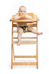 Cute baby girl eating peach and smiling while sitting in high chair