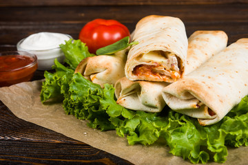 Double burrito with chicken in Caesar sauce on a dark wooden background
