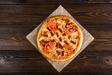 Small mini pizza (mini, miniature) on baking paper on a dark wooden background