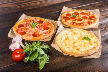 Small mini pizza (mini, miniature) on baking paper on a dark wooden background