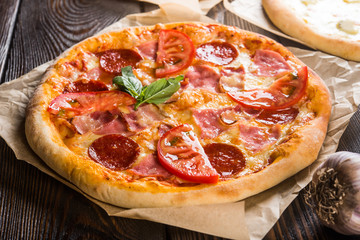 Small mini pizza (mini, miniature) on baking paper on a dark wooden background