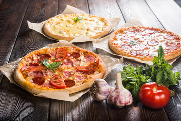 Small mini pizza (mini, miniature) on baking paper on a dark wooden background