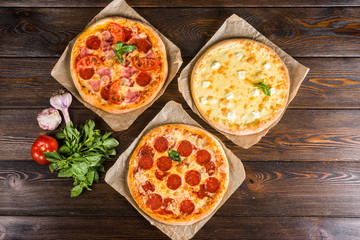 Small mini pizza (mini, miniature) on baking paper on a dark wooden background