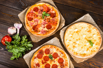 Small mini pizza (mini, miniature) on baking paper on a dark wooden background