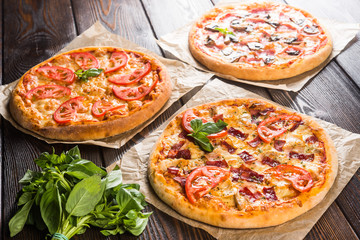 Small mini pizza (mini, miniature) on baking paper on a dark wooden background