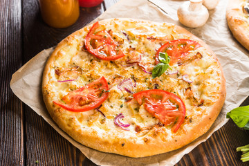 Small mini pizza (mini, miniature) on baking paper on a dark wooden background