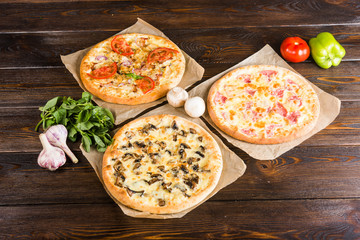 Small mini pizza (mini, miniature) on baking paper on a dark wooden background