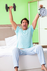 Fototapeta na wymiar Young man in pajamas doing morning exercises 