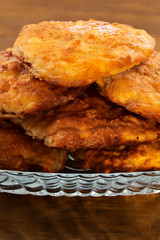 Slim round cheese biscuits in a glass dish on wooden background.