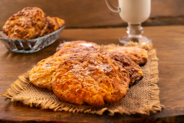 Homemade cookies on a linen napkin, glass of milk, wooden background.