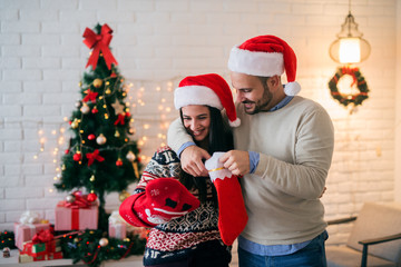 Cheerful beautiful young couple decorating their home for christmas. First christmas eve in their new home.