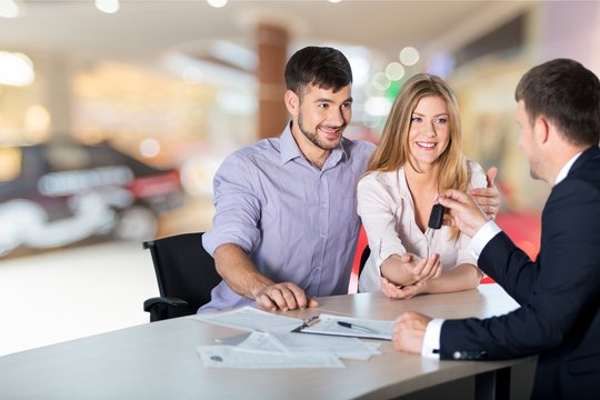 Happy woman with car dealer in auto show or salon