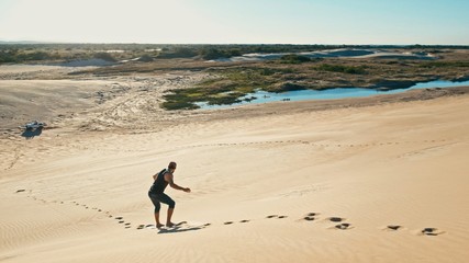 young man sand boarding at the desert sand dunes close to the city