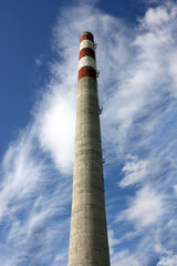 large factory concrete chimney. Steam escapes from the pipe against the sky. Industrial emissions of pollutants into the atmosphere.