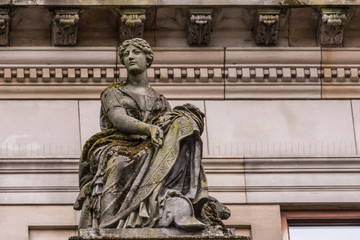 Glasgow, Scotland, UK - June 17, 2012: Closeup of  brown stone and molded statue of sitting woman on facade of City Council building. Mostly shades of brown.