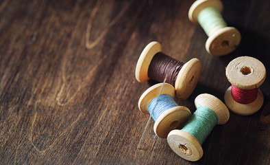 Fototapeta na wymiar Sewing thread on a wooden background. Set of threads on bobbins 
