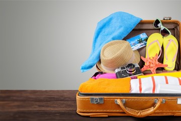 Retro suitcase with travel objects on wooden board on background