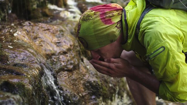 a tourist drinks water from a waterfall