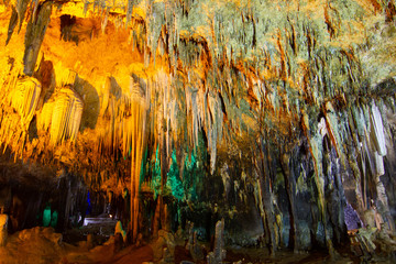 khao bin cave of Thailand, inside cave view of multiple small slender stalactites on the ceiling of a dark cave and a bright orange, Thailand.