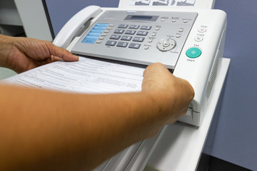 ็Hand man are using a fax machine in the office. Business concept 