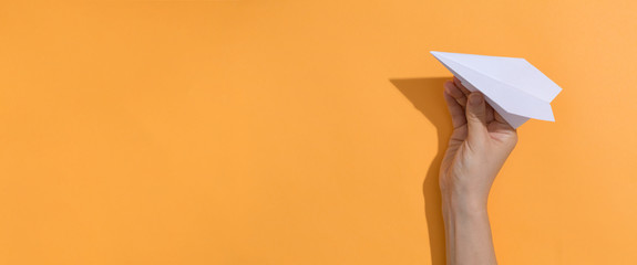 Woman holding a paper air plane on a orange background