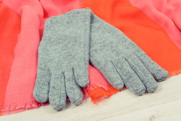 Pair of gray warm womanly gloves and colorful shawl for using in autumn or winter