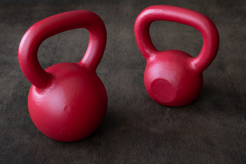 Obraz na płótnie Canvas Two red kettlebells on a brown leather textured background 