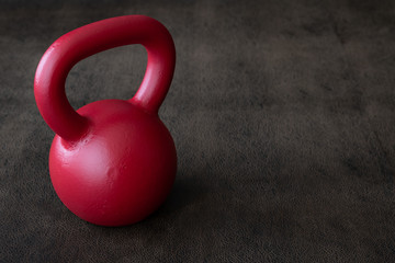 Fototapeta na wymiar Red kettlebell on a brown leather textured background 