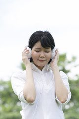 Happy asian woman listening music in garden