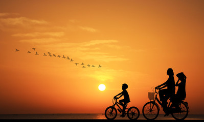 Fototapeta na wymiar silhouette family riding bicycle on sunset