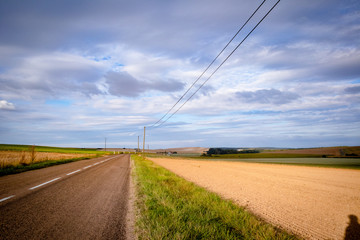 Route traversant les champs sous un ciel de nuages chargés