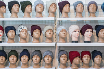 Woolen hats on the silvery heads of the mannequins in the store. a variety of female winter knitted hats on mannequin heads