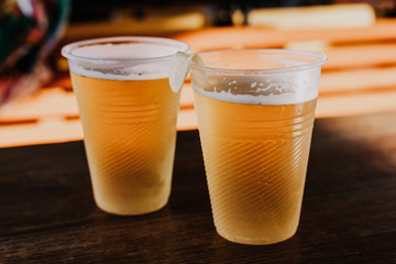 Two plastic glasses with beer stand side by side