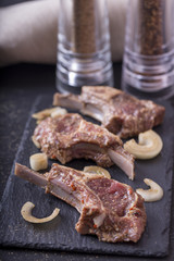 Marinated lamb meat ribs  on dark wooden background. Raw meat  marinated with onion and spices