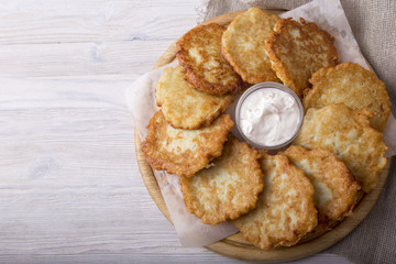 Golden potato pancakes with sour cream. Top view. Copyspace