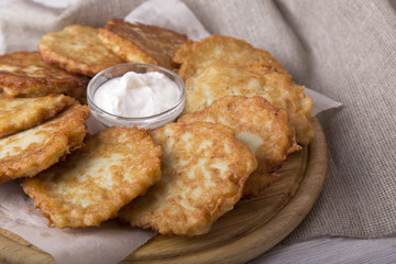 Potato pancakes with sour cream. Homemade draniki on wooden board