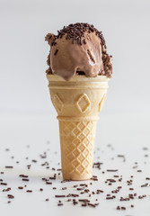 Ice cream flat bottomed single cone standing on white background. Chocolate icecream with sprinkles...