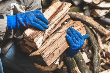 Hands in gloves hold wooden logs