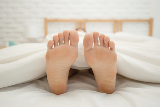 Close up two feet of woman sleep on white bed in bedroom,Feeling relax and comfortable,Healthcare Concept