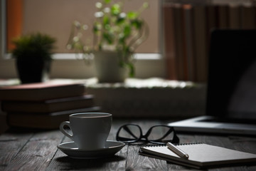 A cup of coffee in the workplace on a wooden table.