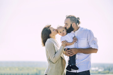 Family mom dad and baby happy with smiles together outdoors in the Park summer portrait