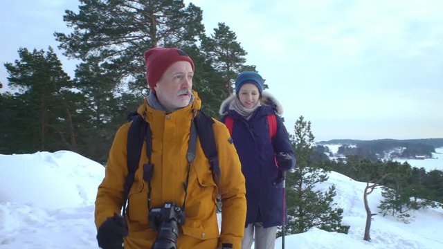 Couple on winter hike in mountains. Backpackers walking on snow in Scandinavia help each other, take pictures and enjoy nature