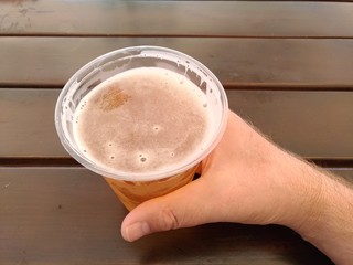 Man's hand holding plastic glass