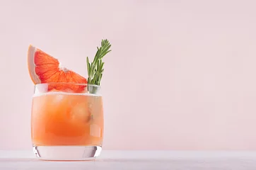 Foto auf Acrylglas Cocktail Kalter Grapefruitcocktail verzierte Zweigrosmarin und Zitrusfrüchte auf rosafarbenem Hintergrund.