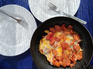 Freshly fried scrambled eggs with sausage, tomatoes