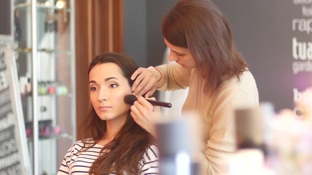 Make up for young beautiful bride in beauty salon - applying powder bruch