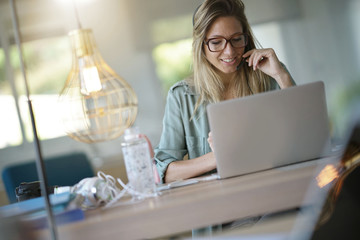 Business girl in home-office using headset